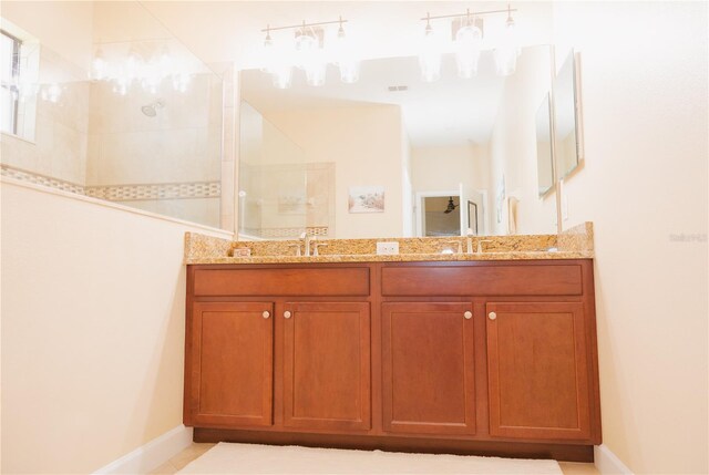 bathroom featuring double vanity, baseboards, walk in shower, and a sink