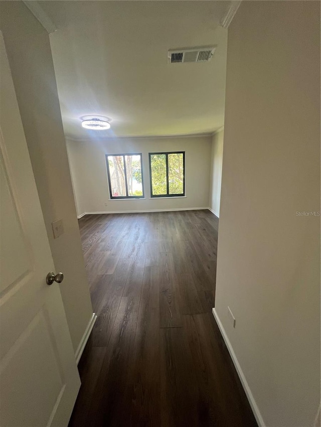 unfurnished room with baseboards, visible vents, and dark wood-style flooring