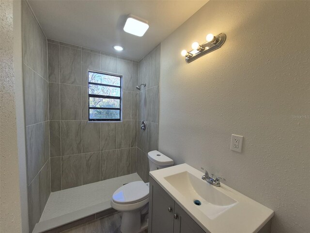 139 Arroyo Pkwy, Ormond Beach, FL 32174 - full bathroom featuring wood finished floors, vanity, a textured wall, a tile shower, and toilet