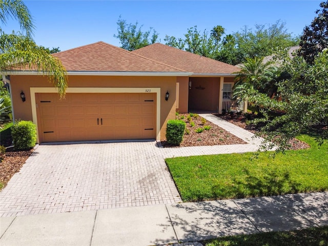523 Shell Creek St, Poinciana, FL 34759 - ranch-style home with an attached garage, a shingled roof, stucco siding, and decorative driveway
