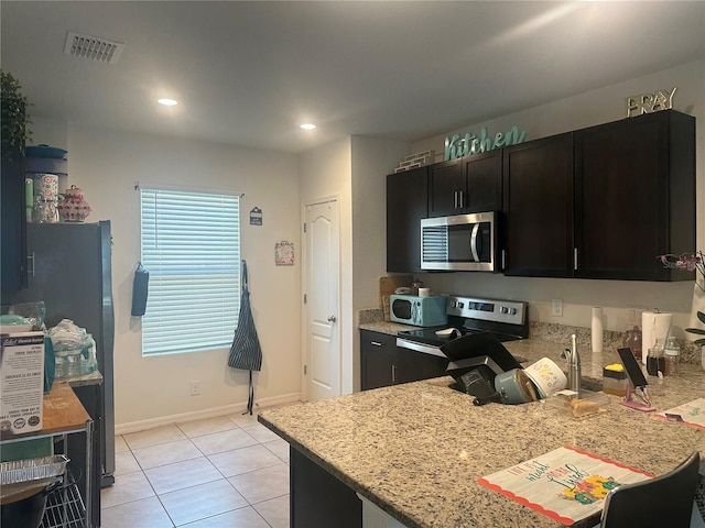 kitchen featuring light tile patterned floors, visible vents, appliances with stainless steel finishes, and dark cabinetry