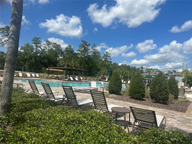 community pool with a patio area and fence