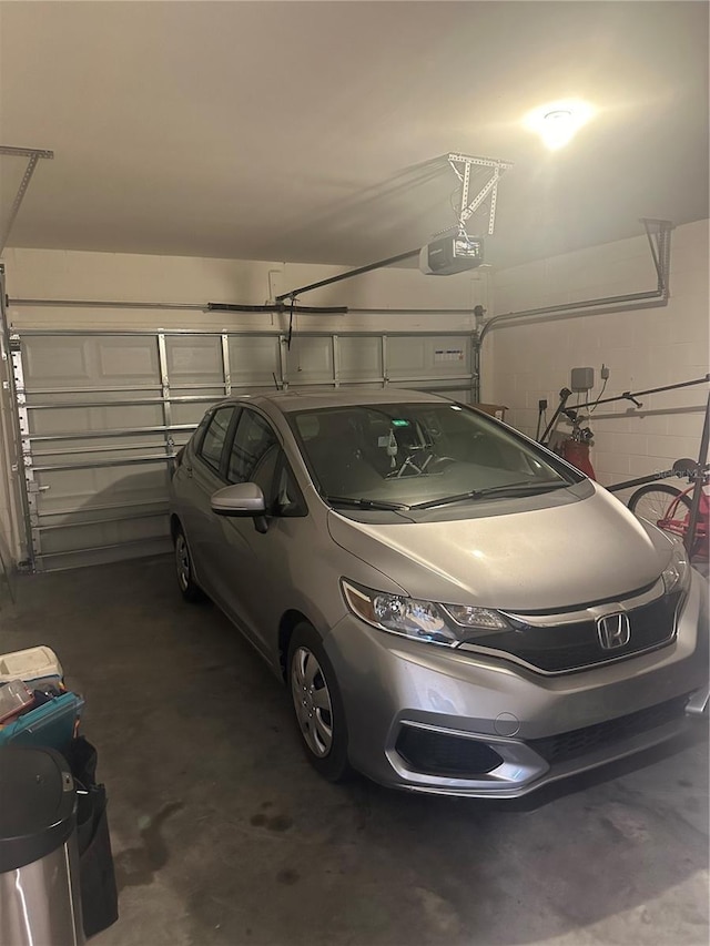 garage with a garage door opener and concrete block wall