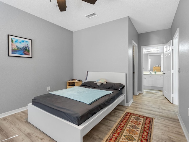 18001 Richmond Place Dr Unit 126, Tampa, FL 33647 - bedroom featuring light wood-type flooring, connected bathroom, a textured ceiling, and ceiling fan