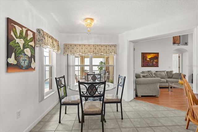 2289 Jessica Ln, Kissimmee, FL 34744 - dining space featuring arched walkways, a textured ceiling, and light tile patterned flooring