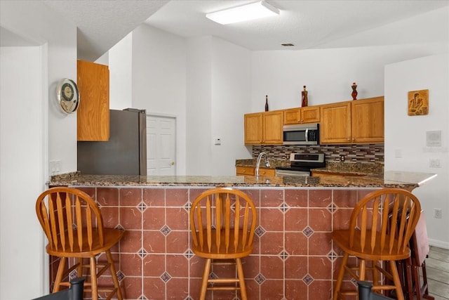 2289 Jessica Ln, Kissimmee, FL 34744 - kitchen with dark stone countertops, stainless steel appliances, backsplash, a peninsula, and visible vents