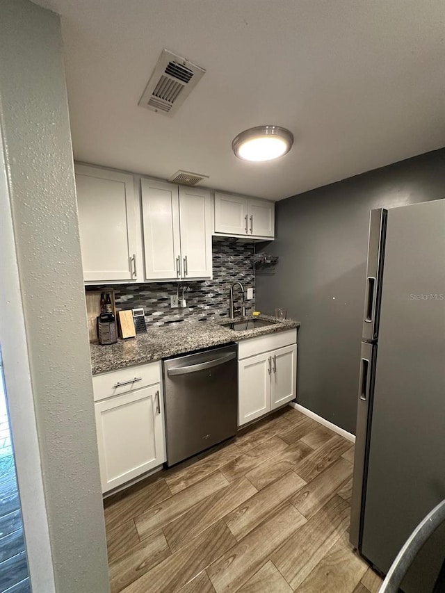 131 Water Front Way Unit 220, Altamonte Springs, FL 32701 - kitchen featuring appliances with stainless steel finishes, decorative backsplash, dark stone countertops, white cabinets, and wood finished floors