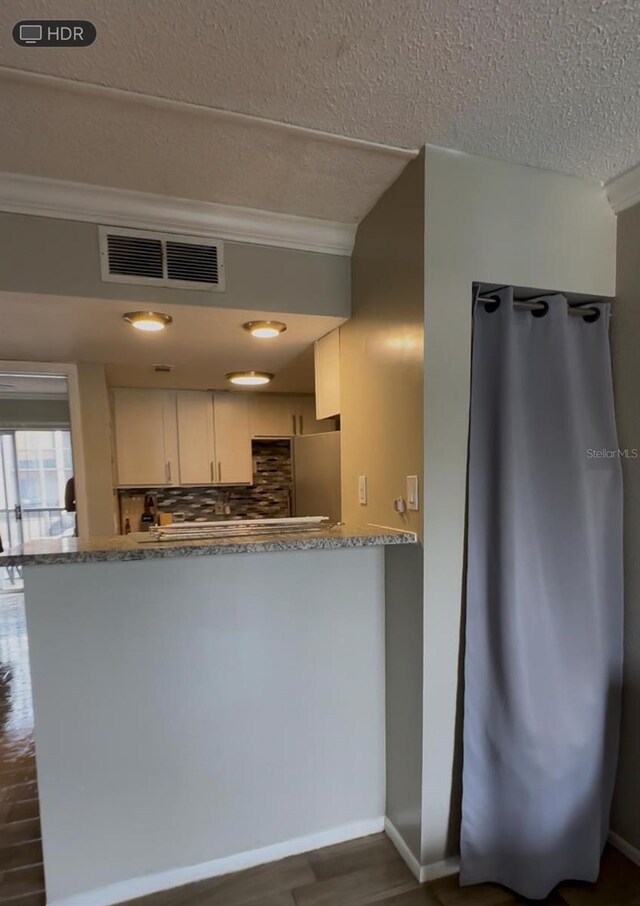 131 Water Front Way Unit 220, Altamonte Springs, FL 32701 - kitchen featuring ornamental molding, a textured ceiling, tasteful backsplash, white cabinetry, and fridge