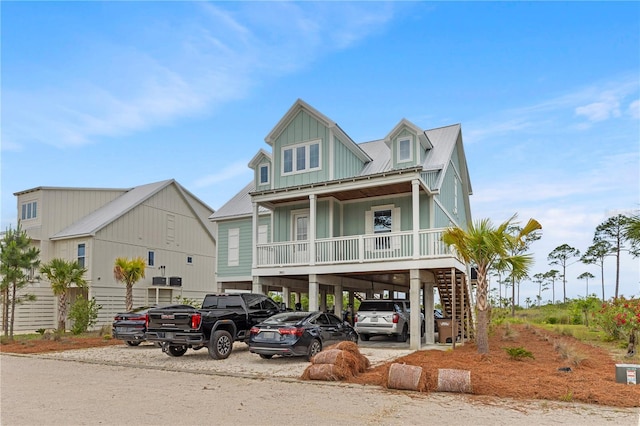beach home featuring a carport, a porch, board and batten siding, metal roof, and stairway