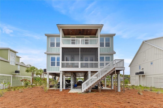 rear view of house featuring a balcony, a sunroom, board and batten siding, stairway, and metal roof