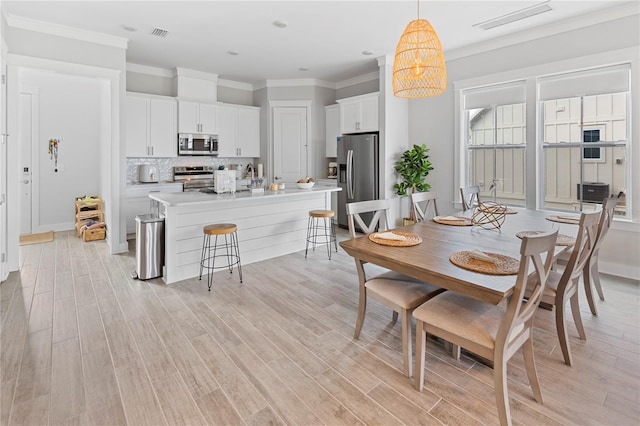 dining room with light wood-type flooring and ornamental molding