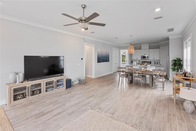 living room with light wood-type flooring, a ceiling fan, baseboards, crown molding, and recessed lighting