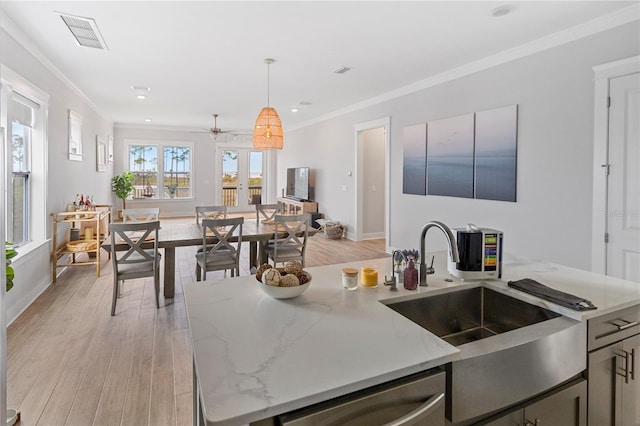kitchen with stainless steel dishwasher, a sink, ornamental molding, light wood-style floors, and ceiling fan