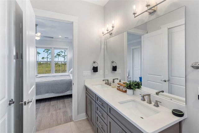 ensuite bathroom featuring double vanity, a ceiling fan, and baseboards