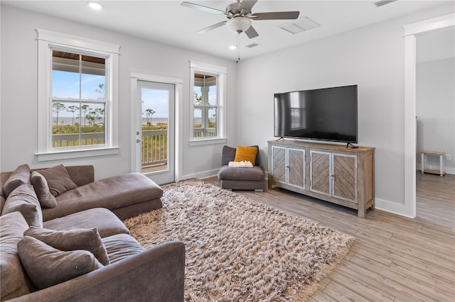 living area featuring healthy amount of natural light, recessed lighting, ceiling fan, wood finished floors, and baseboards