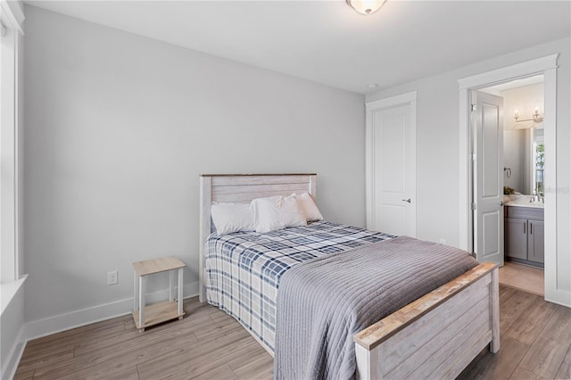 bedroom featuring light wood-style flooring, connected bathroom, baseboards, and a sink