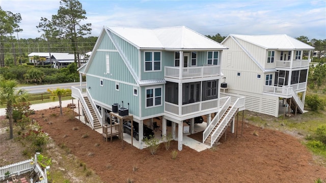back of house featuring stairway, a sunroom, a balcony, and metal roof