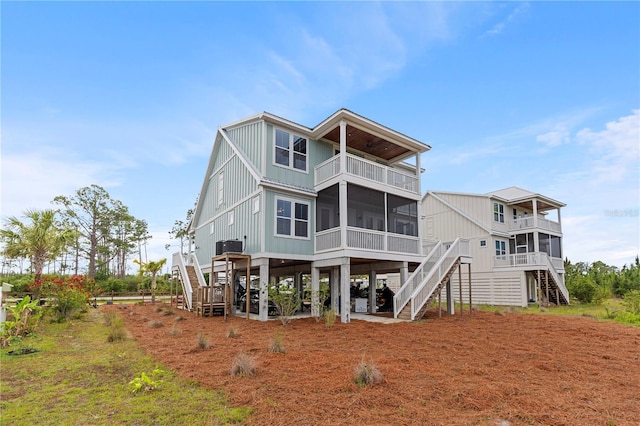 rear view of property featuring stairway, a balcony, a sunroom, and board and batten siding