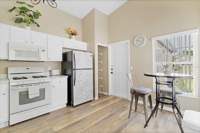 kitchen featuring high vaulted ceiling, light wood-style flooring, white appliances, light countertops, and white cabinetry