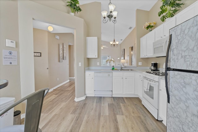 kitchen featuring white cabinets, light wood-type flooring, a notable chandelier, and white appliances