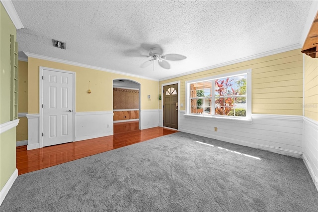 2430 Mill Run Blvd, Kissimmee, FL 34744 - carpeted empty room with a ceiling fan, crown molding, a textured ceiling, wainscoting, and arched walkways