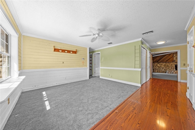 2430 Mill Run Blvd, Kissimmee, FL 34744 - carpeted empty room with a ceiling fan, a textured ceiling, crown molding, wood walls, and wood finished floors