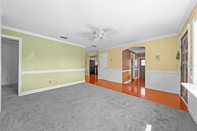 2430 Mill Run Blvd, Kissimmee, FL 34744 - unfurnished living room featuring carpet floors, a ceiling fan, arched walkways, ornamental molding, and wainscoting