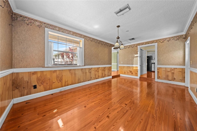 2430 Mill Run Blvd, Kissimmee, FL 34744 - empty room featuring wood finished floors, a textured ceiling, a chandelier, ornamental molding, and wainscoting