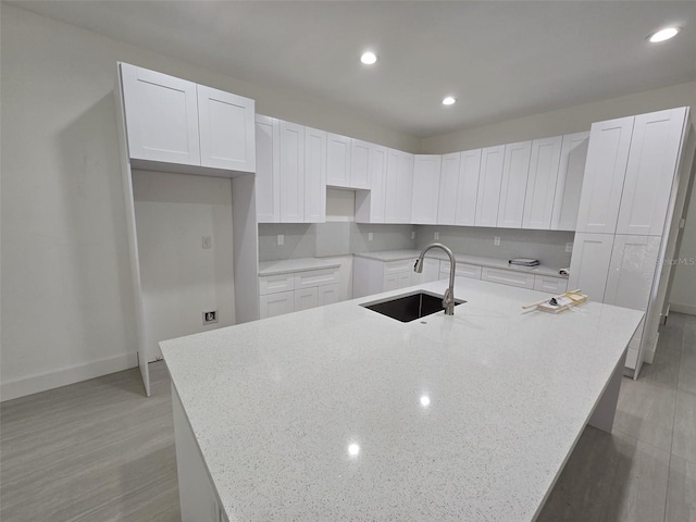 4098 New Milford St, North Port, FL 34288 - kitchen featuring a sink, a spacious island, white cabinets, light stone countertops, and recessed lighting
