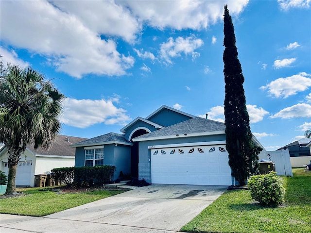 ranch-style house with a shingled roof, a front lawn, stucco siding, an attached garage, and driveway