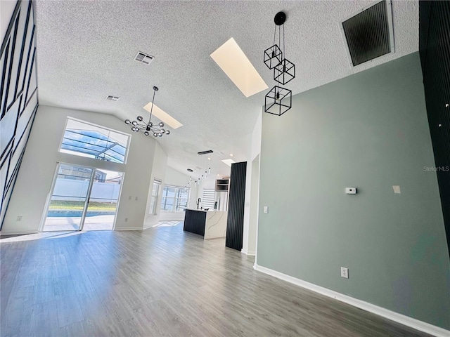 unfurnished living room with a textured ceiling, visible vents, and high vaulted ceiling