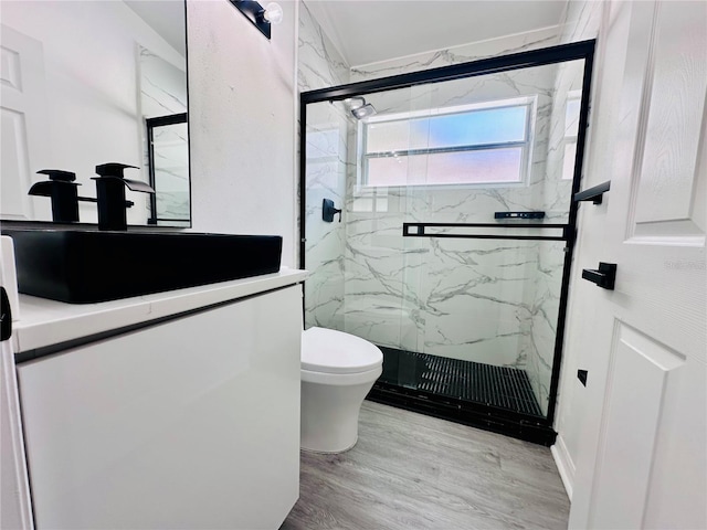 bathroom with wood finished floors, toilet, vanity, and a marble finish shower