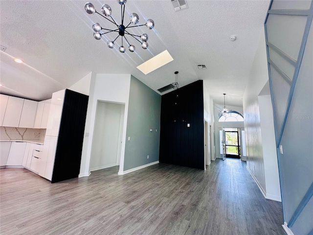 unfurnished living room featuring high vaulted ceiling, a notable chandelier, a textured ceiling, and visible vents