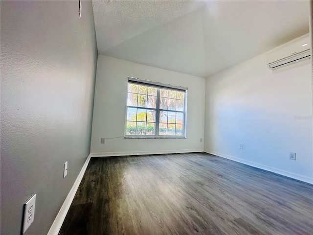 spare room with dark wood-type flooring, a wall mounted air conditioner, lofted ceiling, and baseboards