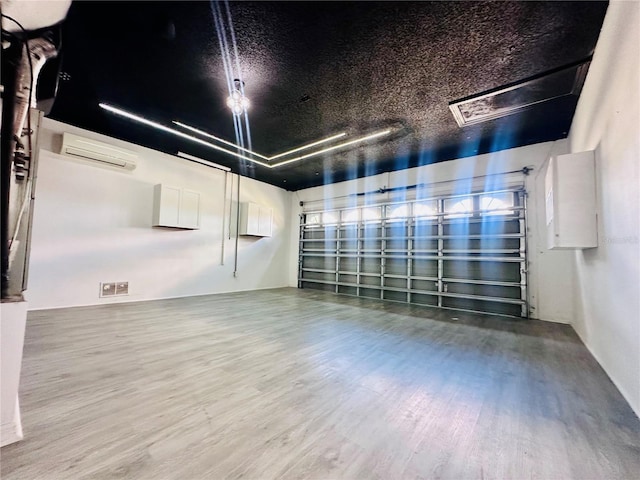 empty room with a wall mounted AC, wood finished floors, and visible vents