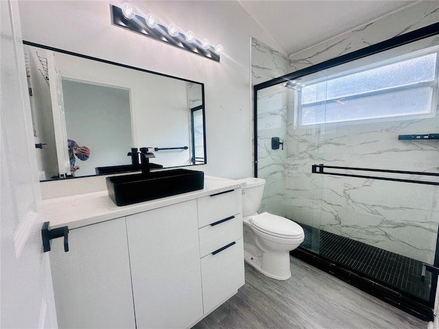 bathroom with a marble finish shower, a wealth of natural light, toilet, vaulted ceiling, and wood finished floors