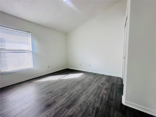 spare room with lofted ceiling, dark wood-style flooring, a textured ceiling, and baseboards