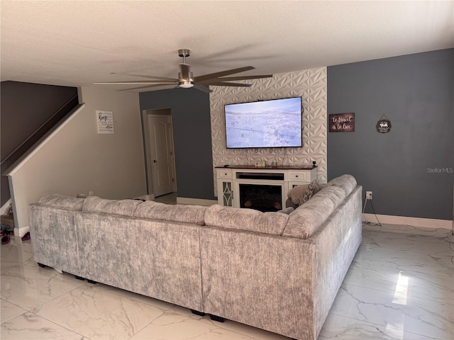 living area featuring baseboards, ceiling fan, a fireplace, and marble finish floor