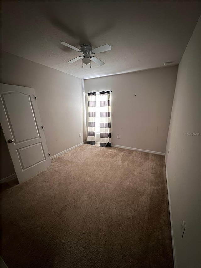 spare room with ceiling fan, carpet, and baseboards