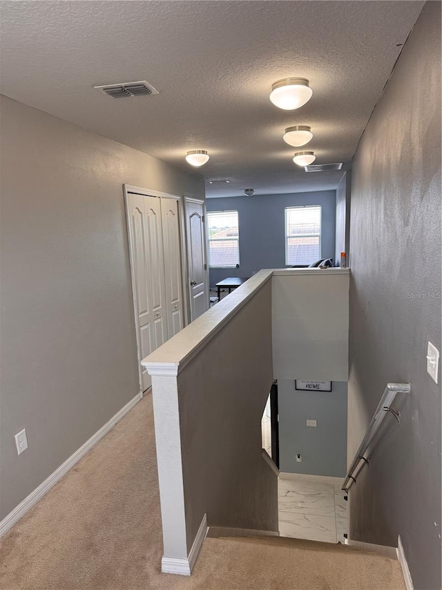 staircase with baseboards, visible vents, a textured ceiling, and carpet