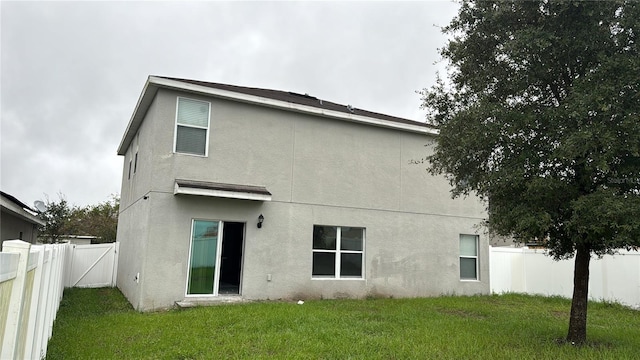 rear view of property with a fenced backyard, stucco siding, and a yard