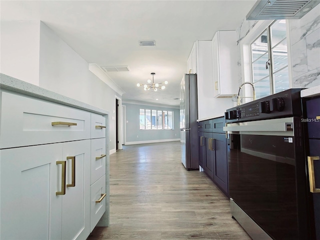 905 W 11th Ave, Mount Dora, FL 32757 - kitchen with a chandelier, white cabinetry, wood finished floors, baseboards, and freestanding refrigerator