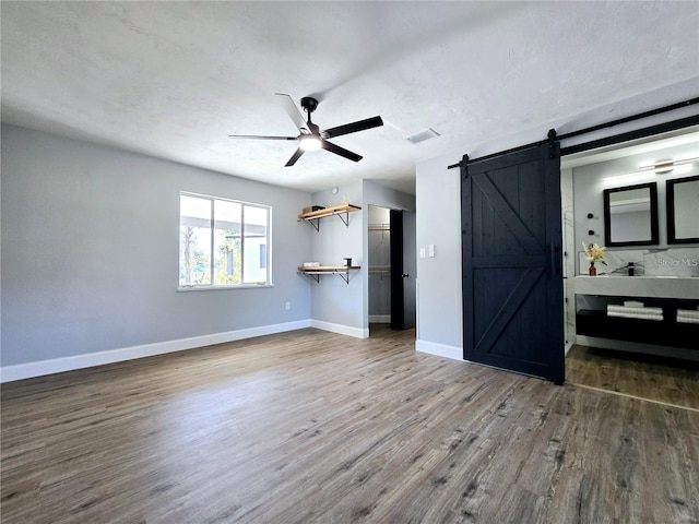 905 W 11th Ave, Mount Dora, FL 32757 - unfurnished bedroom with a barn door, wood finished floors, baseboards, and ceiling fan