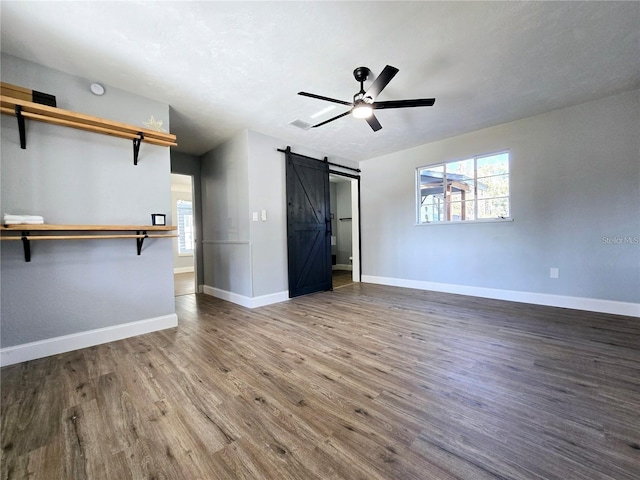 905 W 11th Ave, Mount Dora, FL 32757 - unfurnished living room with a barn door, wood finished floors, healthy amount of natural light, and baseboards