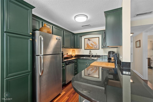 4820 Conway Rd Unit 130, Orlando, FL 32812 - kitchen featuring appliances with stainless steel finishes, a sink, dark countertops, green cabinets, and crown molding