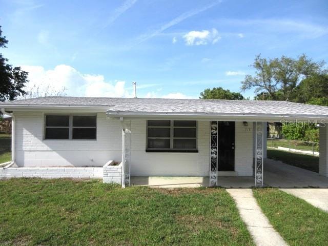 ranch-style house with a shingled roof, a front lawn, and an attached carport