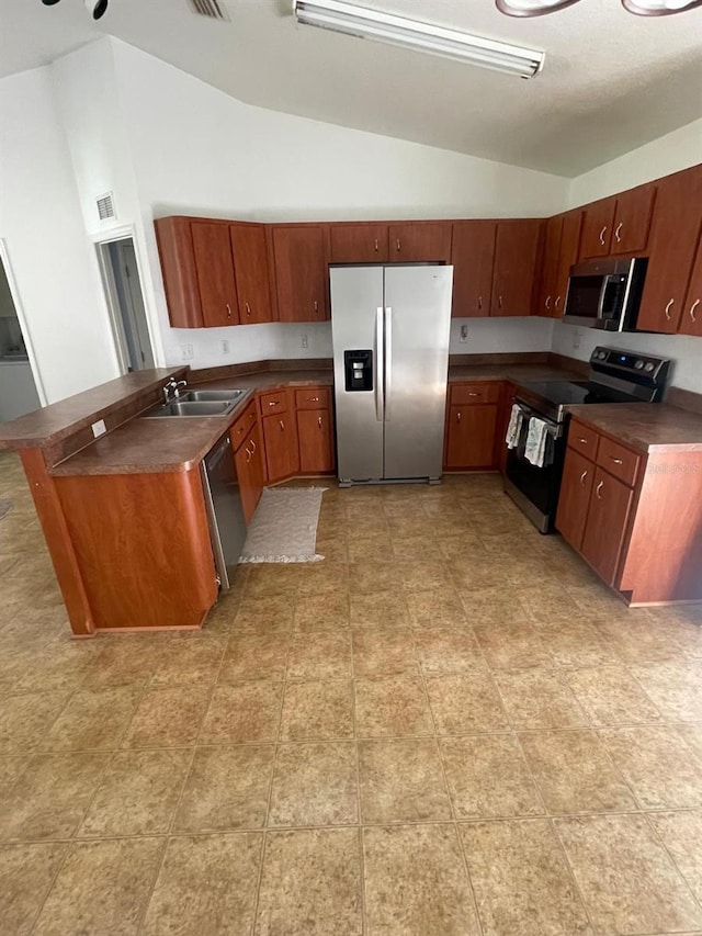 kitchen with vaulted ceiling, dark countertops, a sink, stainless steel appliances, and visible vents