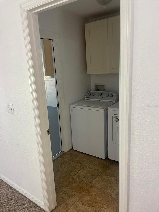 clothes washing area featuring washing machine and dryer and cabinet space