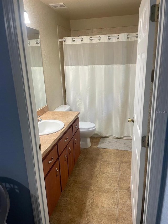 full bath with a textured wall, visible vents, toilet, and vanity