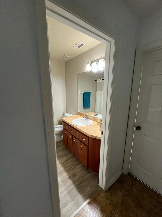 bathroom with visible vents, toilet, and vanity